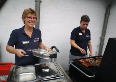 Das Küchenteam steht beim Sommerfest hinter dem Grill