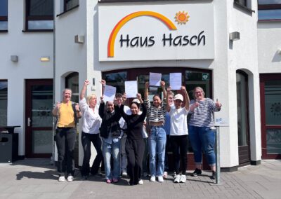 Freudensprünge der Einrichtungsleitung, Kolleginnen und Azubis mit Endzeugnis in der Hand