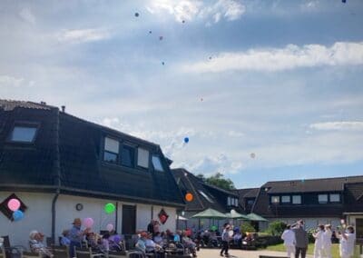 Bewohner lassen im Garten des Hauses Luftballons steigen.